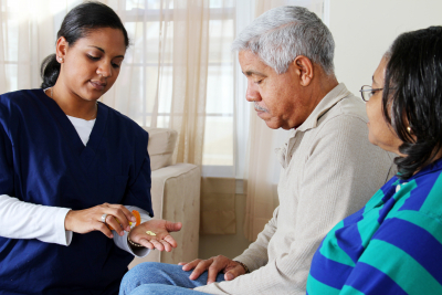 female caregiver handing meds to elder man