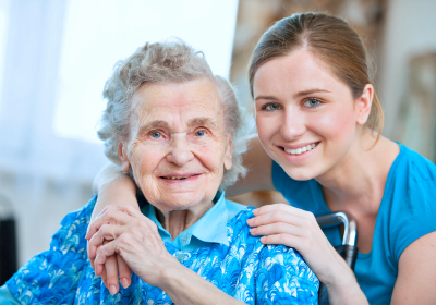 elder woman and her caregiver smiling