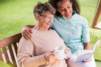 caregiver reading a book to an elder woman